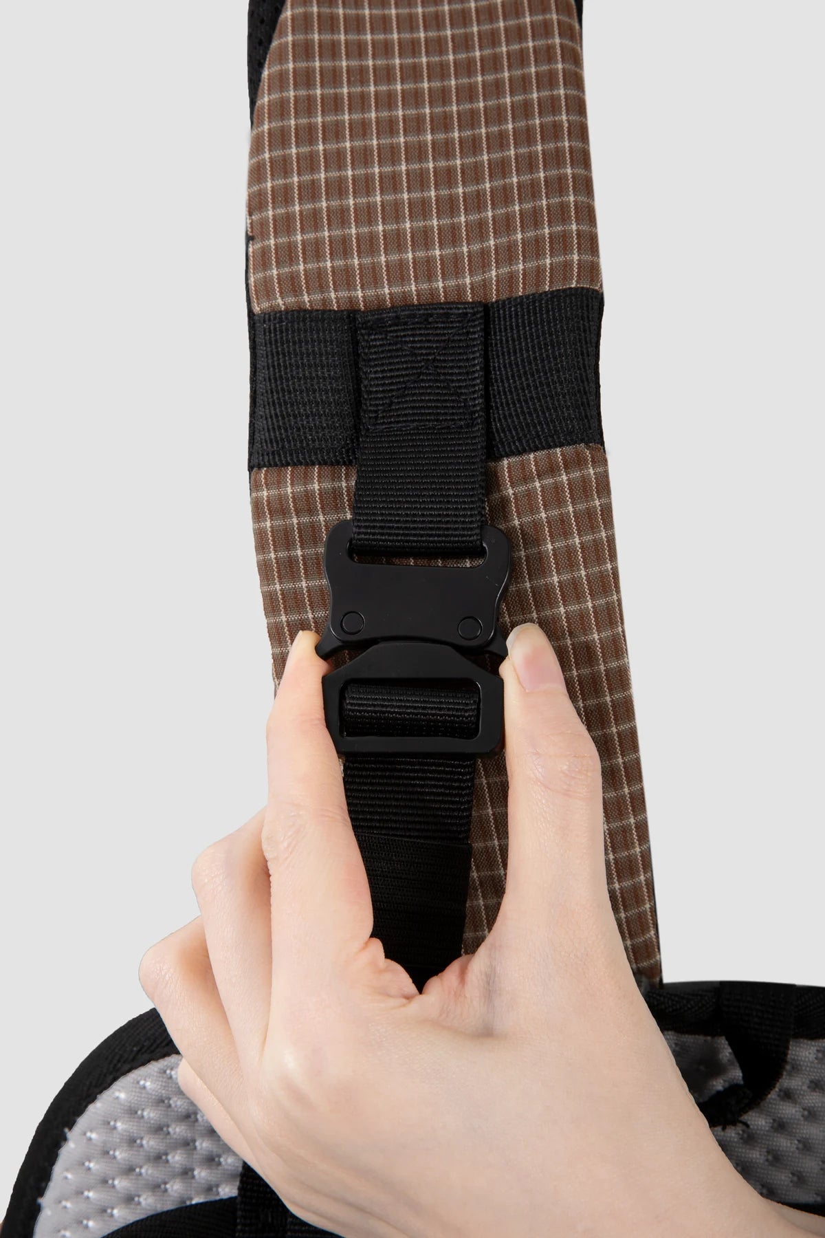 Adjustable shoulder strap buckle shown by hand